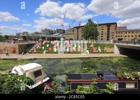 Tandis que le verrouillage Covid facilite l'herbe artificielle est remis sur les marches de Granary Square, avec des séparateurs pop à l'envelly funky pour aider à distancer les sociaux, à Kings Cross, au nord de Londres, Royaume-Uni Banque D'Images