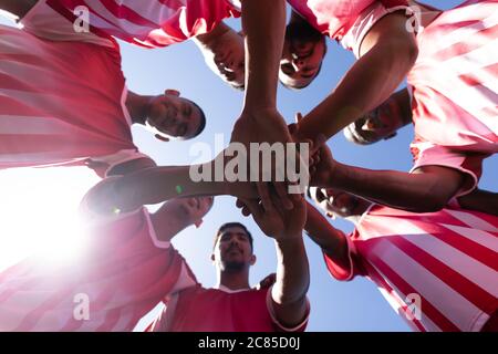 Vue à angle bas de l'équipe multi-ethnique de cinq joueurs de football de côté portant un entraînement de bande d'équipe sur un terrain de sport au soleil, debout à circl Banque D'Images