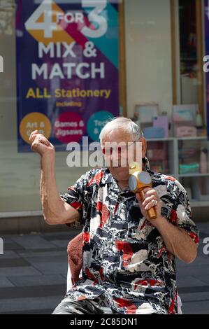 Slough, Berkshire, Royaume-Uni. 21 juillet 2020. Un homme chante aux acheteurs et joue de la musique optimiste pour élever l'esprit dans Slough High Street. Crédit : Maureen McLean/Alay Banque D'Images