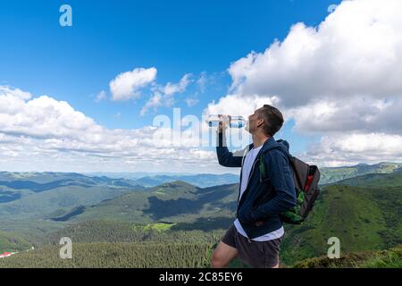 Randonneur se relaxant au sommet de la montagne et boire de l'eau en bouteille Banque D'Images