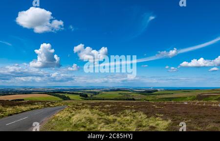 Lammermuir Hills, East Lothian, Écosse, Royaume-Uni, 21st juillet 2020.Météo au Royaume-Uni : soleil d'été avec la température qui monte à 20 degrés centigrade et un ciel clair avec une vue imprenable sur la longue distance du nord sur les landes et la campagne de Lothian est.Le Firth of Forth avec Bass Rock est visible avec une route de campagne vide menant à la distance Banque D'Images