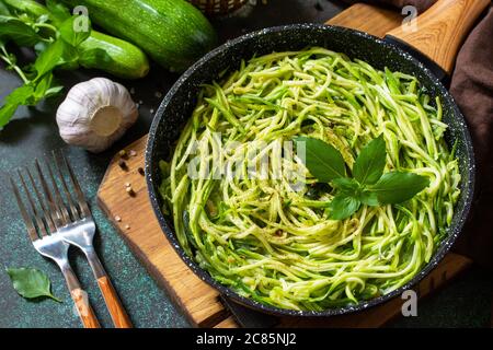 Nourriture végétalienne saine, plat à carb bas. Nouilles courgettes cuites au basilic et à l'ail dans une casserole en fonte sur un comptoir en pierre. Banque D'Images