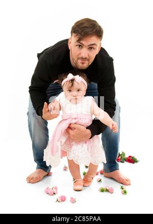 Portrait vertical du mode de vie d'un jeune père aidant sa fille à marcher sur son premier anniversaire. Banque D'Images