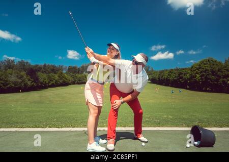 Golf professionnel enseignant une femme étudiant de l'aire d'échauffement Banque D'Images