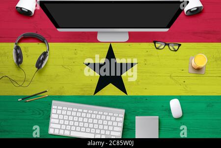 Arrière-plan du drapeau du Ghana avec casque, clavier d'ordinateur et souris sur la table du bureau national.vue du dessus avec espace pour copier.pose à plat. Banque D'Images