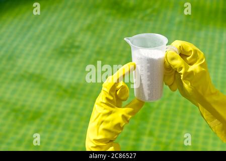ajout de poudre de chlore pour la piscine pour enlever les algues et désinfecter l'eau. concept de soins gonflables pour la piscine. Banque D'Images