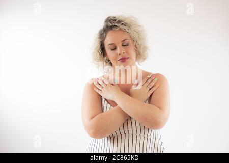 Jeune femme blonde souriante avec ses mains croisées Banque D'Images