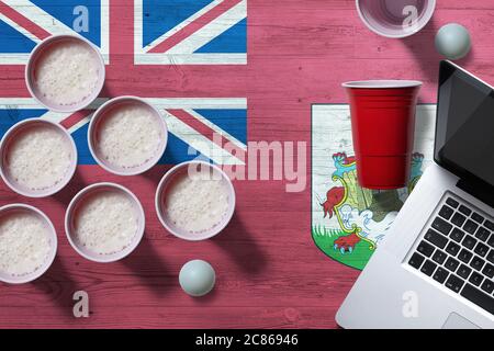 Drapeau des Bermudes avec tasses de bière-pong en plastique et ordinateur portable sur table nationale en bois, vue sur le dessus. Jeu de pong de bière. Banque D'Images