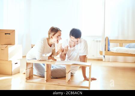 Jeune couple installant des meubles dans une nouvelle maison avec instruction Banque D'Images