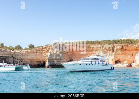 Différents types de bateaux en face des grottes de Benagil et de la plage avec des touristes, Algarve, Portugal Banque D'Images