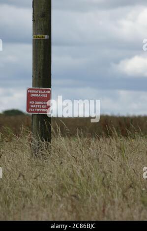 Un panneau sur le poteau télégraphique montrant Private Land ( Organic) & No Fly Tipping ou Garden Waste sur les terres arables à Tetbury, Gloucestershire Royaume-Uni Banque D'Images