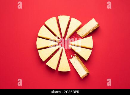 Cheesecake crémeux coupé en tranches avec section intérieure, isolé sur fond rouge. Vue de dessus de délicieuses tranches de tarte au fromage. Gâteau en tranches. Dessert de Noël. Banque D'Images