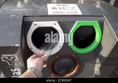 Quelqu'un met du verre dans un conteneur de déchets souterrain du village de Bergen. Ouvertures pour verre blanc, vert et marron. Hollande, janvier Banque D'Images