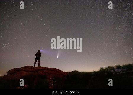 Figure unique debout sur un TOR regardant le ciel Comet Neowise traînant au-dessus de Little mis Tor sur Dartmoor. Banque D'Images