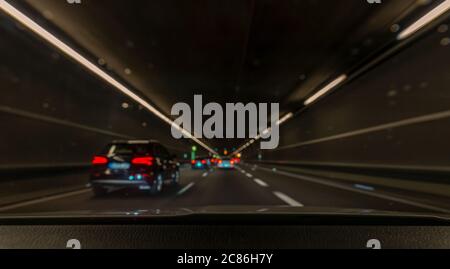 Ambiance ivre et conduite : vue floue de l'intérieur d'une voiture par la fenêtre avant avec d'autres voitures dans un tunnel - lignes de conduite. Banque D'Images