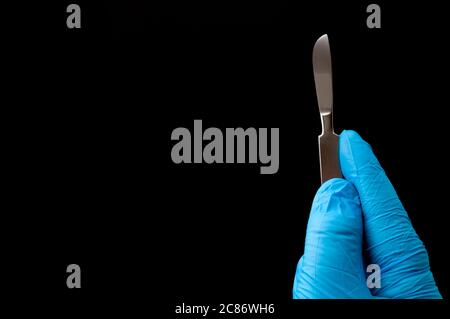 Instruments chirurgicaux en salle d'opération et médecin effectuant la chirurgie thème concept avec une main de chirurgien portant des gants en latex bleu et tenant un scalpel Banque D'Images