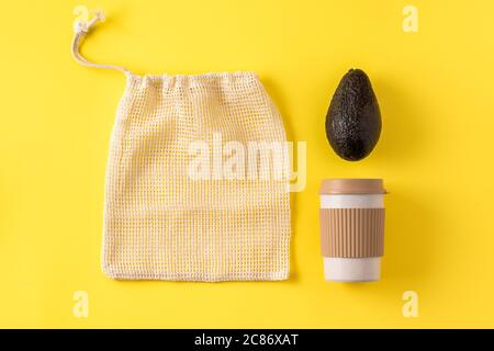 Gobelet écologique portable, sac de fruits et légumes, avocat sur surface jaune. Tasse à café, sac pour l'épicerie, légumes. Flat lay, vue de dessus, mise en page créative. Banque D'Images