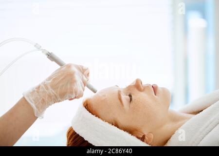 Vue latérale du patient en cours d'femelle anti-vieillissement du visage la procédure dans le centre de beauté. Du visage rajeunissant traitement gaz-liquide, Close up. Banque D'Images