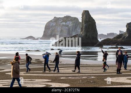 Bandon by the Sea, Oregon / USA - février 21 2020: Femme marchant dans un labyrinthe de sable avec une caméra embarquée et un petit chien dans son manteau. Banque D'Images