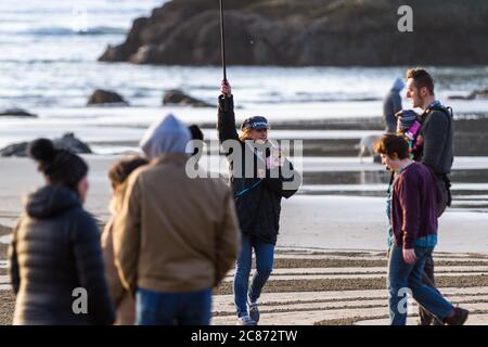 Bandon by the Sea, Oregon / USA - février 21 2020: Femme marchant dans un labyrinthe de sable avec une caméra embarquée et un petit chien dans son manteau. Banque D'Images