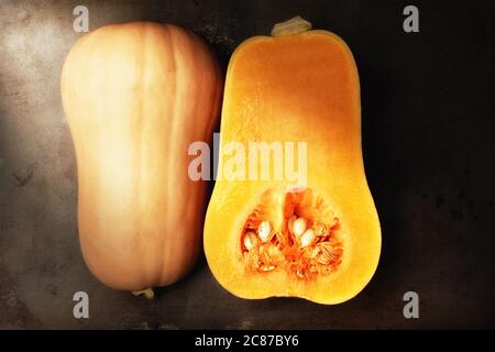 Courge muscourbeurelle coupée en deux montrant l'intérieur et l'extérieur. Format horizontal de pose à plat avec lumière latérale chaude. Banque D'Images