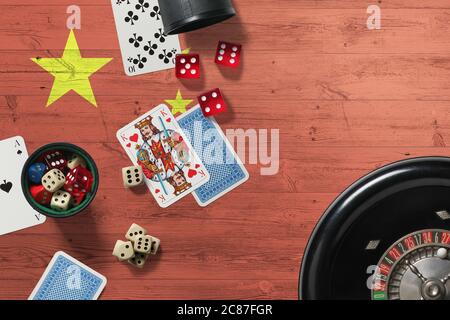 Thème casino de Chine. Jeu de poker Aces, cartes et jetons sur table rouge avec drapeau national en bois. Jeux et Paris. Banque D'Images