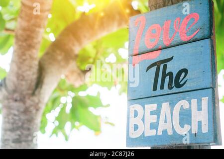 J'adore le mot de plage sur bois pendre sur l'arbre à côté de la plage d'été arrière-plan. Banque D'Images