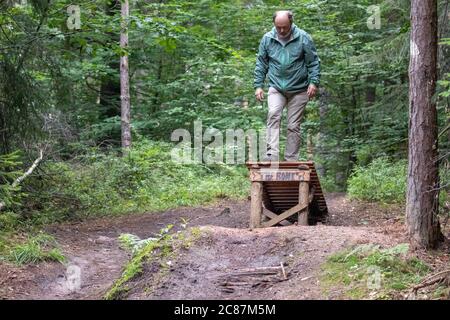 17 juillet 2020, Bavière, Nuremberg: Hans-Joachim Ulrich, garde-forestier de la forêt bavaroise, regarde un saut à ski dans le Reichswald de Nuremberg qui a été construit par les motards eux-mêmes. Au milieu de la forêt, il y a de hauts sauts de ski dans de nombreux endroits - auto-construit avec des planches et des troncs d'arbre et pas toujours sans danger. En raison des dommages à la forêt et à la nature, mais aussi en raison du danger des accidents, certains sauts de ski sont déchirés. (À dpa 'l'ardeur de la construction dans la forêt: Des problèmes avec les pistes illégales de VTT') photo: Daniel Karmann/dpa Banque D'Images