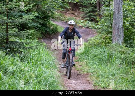 17 juillet 2020, Bavière, Nuremberg: Nora Beyer de la Nuremberg DIMB (German Initiative Mountain Bike), fait un sentier dans le Reichswald de Nuremberg. Au milieu de la forêt, il y a non seulement des sentiers et des virages abrupts mais aussi de nombreux sauts de ski de haut niveau - auto-construit avec des planches et des troncs d'arbre et pas toujours sans danger. Le DIMB et Bayerische Staatsforsten recherchent des solutions pour enlever les structures dangereuses d'une part, mais surtout pour préserver autant de pistes de descente existantes que possible. (À dpa 'l'ardeur de la construction dans la forêt: Des problèmes avec les pistes illégales de VTT' Banque D'Images