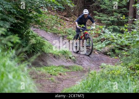 17 juillet 2020, Bavière, Nuremberg: Nora Beyer de la Nuremberg DIMB (German Initiative Mountain Bike), fait un sentier dans le Reichswald de Nuremberg. Au milieu de la forêt, il y a non seulement des sentiers et des virages abrupts mais aussi de nombreux sauts de ski de haut niveau - auto-construit avec des planches et des troncs d'arbre et pas toujours sans danger. Le DIMB et Bayerische Staatsforsten recherchent des solutions pour enlever les structures dangereuses d'une part, mais surtout pour préserver autant de pistes de descente existantes que possible. (À dpa 'l'ardeur de la construction dans la forêt: Des problèmes avec les pistes illégales de VTT' Banque D'Images