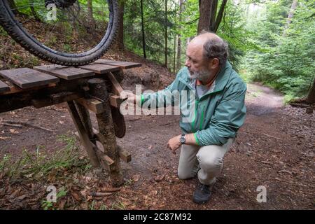 17 juillet 2020, Bavière, Nuremberg: Hans-Joachim Ulrich, garde-forestier de la forêt bavaroise, regarde un saut à ski dans le Reichswald de Nuremberg qui a été construit par les motards eux-mêmes. Au milieu de la forêt, il y a de hauts sauts de ski dans de nombreux endroits - auto-construit avec des planches et des troncs d'arbre et pas toujours sans danger. En raison des dommages à la forêt et à la nature, mais aussi en raison du danger des accidents, certains sauts de ski sont déchirés. (À dpa 'l'ardeur de la construction dans la forêt: Des problèmes avec les pistes illégales de VTT') photo: Daniel Karmann/dpa Banque D'Images