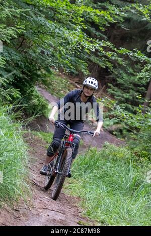 17 juillet 2020, Bavière, Nuremberg: Nora Beyer de la Nuremberg DIMB (German Initiative Mountain Bike), fait un sentier dans le Reichswald de Nuremberg. Au milieu de la forêt, il y a non seulement des sentiers et des virages abrupts mais aussi de nombreux sauts de ski de haut niveau - auto-construit avec des planches et des troncs d'arbre et pas toujours sans danger. Le DIMB et Bayerische Staatsforsten recherchent des solutions pour enlever les structures dangereuses d'une part, mais surtout pour préserver autant de pistes de descente existantes que possible. (À dpa 'l'ardeur de la construction dans la forêt: Des problèmes avec les pistes illégales de VTT' Banque D'Images