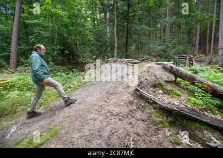 17 juillet 2020, Bavière, Nuremberg: Hans-Joachim Ulrich, forestier de la forêt bavaroise, envisage un saut à ski dans le Reichswald de Nuremberg construit par les motards eux-mêmes, qui doit être enlevé. Au milieu de la forêt, il y a de hauts sauts de ski dans de nombreux endroits - auto-construit avec des planches et des troncs d'arbre et pas toujours sans danger. En raison des dommages causés à la forêt et à la nature, mais aussi en raison du danger d'accidents, certains sauts à ski seront démolis. (À dpa 'l'ardeur de la construction dans la forêt: Des ennuis avec les pistes illégales de VTT') photo: Daniel Karman Banque D'Images