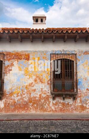 Façade de maison de style colonial dans la ville de la Antigua Guatemala, avec cheminée et balcons en fer forgé, rue pavée et ciel bleu. Banque D'Images