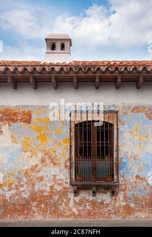 Façade de maison de style colonial dans la ville de la Antigua Guatemala, avec cheminée et balcons en fer forgé, rue pavée et ciel bleu. Banque D'Images