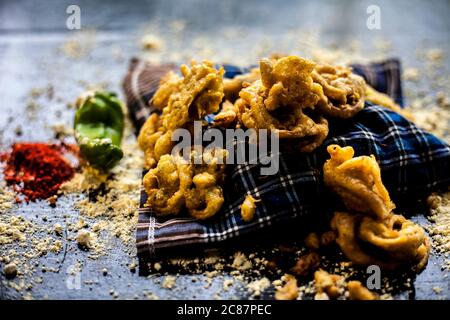 Célèbre kanda bhaji ou kanda bhajiya ou kanda pakora dans un récipient sur une surface noire avec la farine de pois chiches, les épices, et tous les autres ingrédients pour Banque D'Images