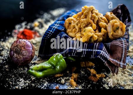 Célèbre Kanda bhaji ou Kanda bhajiya ou Kanda pakora dans un récipient sur une surface noire avec de la farine de pois chiches, des épices, des oignons, et tous les autres ingrédients Banque D'Images