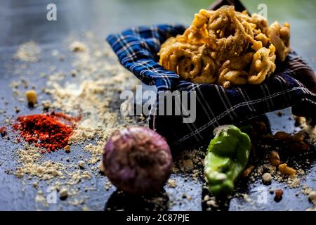 Célèbre Kanda bhaji ou Kanda bhajiya ou Kanda pakora dans un récipient sur une surface noire avec de la farine de pois chiches, des épices, des oignons, et tous les autres ingrédients Banque D'Images