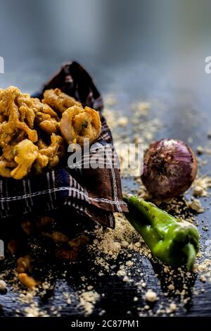 Célèbre Kanda bhaji ou Kanda bhajiya ou Kanda pakora dans un récipient sur une surface noire avec de la farine de pois chiches, des épices, des oignons, et tous les autres ingrédients Banque D'Images
