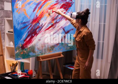 Artiste portant un casque vr et un tableau en studio d'art. Peinture d'art moderne sur toile, création, contemporain et succès artiste de beaux-arts dessinant chef-d'œuvre Banque D'Images