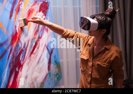 Peintre créatif avec casque vr peint sur toile dans un studio d'art. Peinture d'art moderne sur toile, création, contemporain et succès artiste de beaux-arts dessinant chef-d'œuvre Banque D'Images