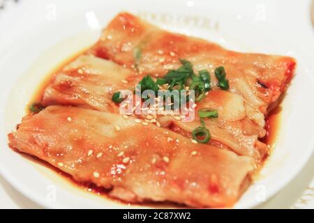 Vue rapprochée du Chee cheong doux ou du rouleau de nouilles de riz servi sur une assiette blanche, parsemé d'oignons de printemps et de graines de sésame, Singapour Banque D'Images