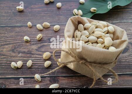 Pistaches dans le sac sur la table en bois Banque D'Images