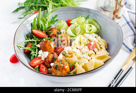 Pâtes italiennes. Conchiglie avec boulettes de viande, fromage feta et salade sur fond clair. Dîner. Concept de Slow Food Banque D'Images