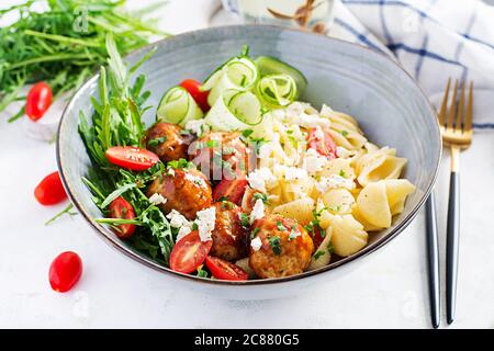 Pâtes italiennes. Conchiglie avec boulettes de viande, fromage feta et salade sur fond clair. Dîner. Concept de Slow Food Banque D'Images