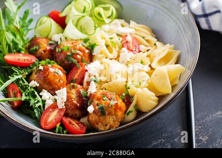 Pâtes italiennes. Conchiglie avec boulettes de viande, fromage feta et salade sur fond sombre. Dîner. Concept de Slow Food Banque D'Images