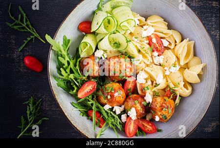 Pâtes italiennes. Conchiglie avec boulettes de viande, fromage feta et salade sur fond sombre. Dîner. Vue de dessus, au-dessus de la tête. Concept de Slow Food Banque D'Images