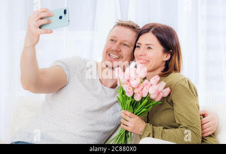 Couple de famille prenant selfie avec bouquet de fleurs sur téléphone portable Banque D'Images
