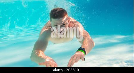 Jeune homme attrayant nager sous l'eau dans le sondage de natation Banque D'Images