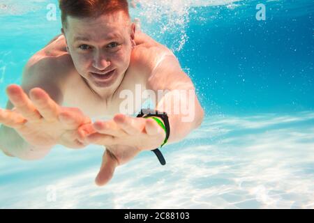 Jeune homme attrayant nageant sous l'eau avec les yeux ouverts Banque D'Images